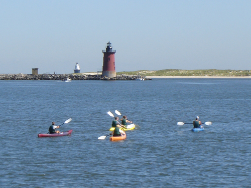 Kayakers paddle in the Delaware Bay with the Cape Henlopen Lighthouse in the distance. Photo by Clarke Rupert.